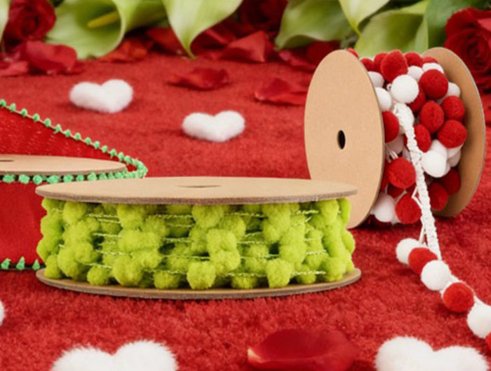 Pom pom trims (red, green, white) on red background with roses – for festive crafts