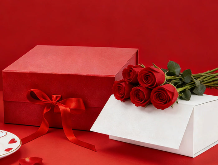 Red roses bouquet, gift box, romantic Valentine's Day gift setup on red background.