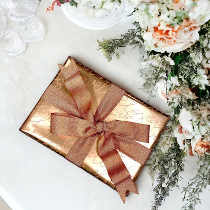 Gifts wrapped in floral, "love" script, polka-dot metallic papers + satin bows; wedding gifting.