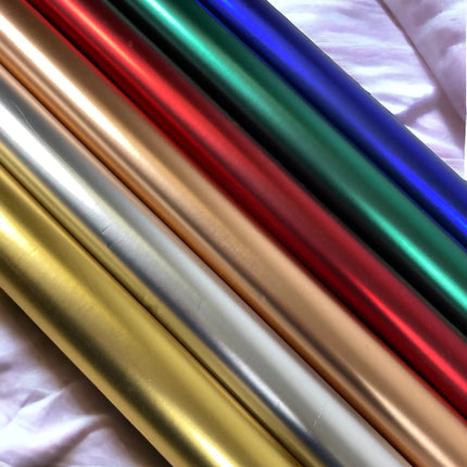 Assorted metallic matte wrapping paper rolls in gold, silver, rose gold, red, green, blue, for gift wrapping