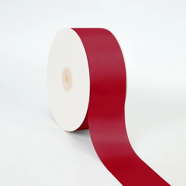 Roll of scarlet double-face satin ribbon, unspooled section, sleek lustrous finish.