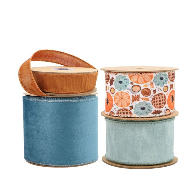 Four spools of ribbons: orange textured, blue velvet, fall-themed (pumpkins/pies), and light blue woven.