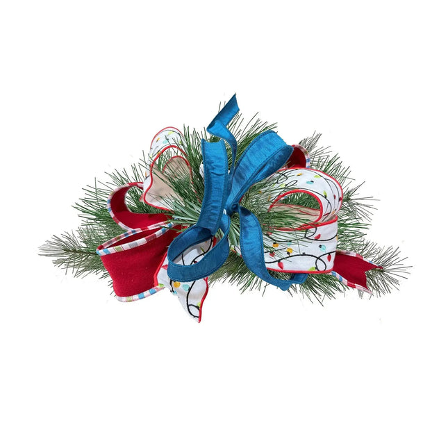Festive Christmas centerpiece with blue, red plaid-trim, and light-patterned ribbons on green pine.