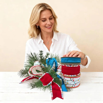 Vibrant Christmas ribbons – blue, red with plaid accents, and light-themed designs – showcased in a pine arrangement.