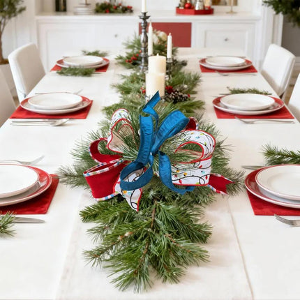 Christmas ribbons – blue, red plaid-trim, light-patterned – adorn a pine centerpiece on a holiday dining table.