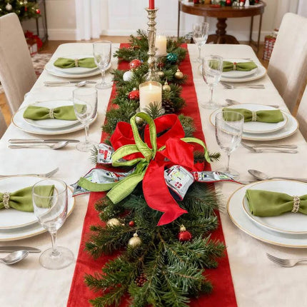 On a Christmas dining table, the centerpiece with pine branches showcases red, green, and gray snowman-embroidered ribbons.