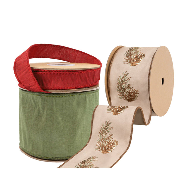 Three spools of Christmas ribbons: a beige ribbon with pine cone and branch embroidery, a solid green ribbon, and a red ribbon.