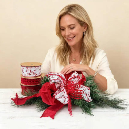 Christmas decor with candy-cane, red pom-pom, and solid red ribbons adorning green pine.
