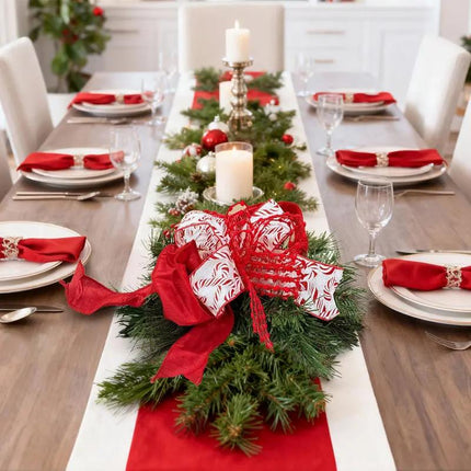 A Christmas dining table has a pine centerpiece with candy-cane and red ribbons,creating a festive vibe.