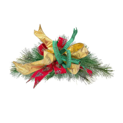 A Christmas pine decor with three ribbons: metallic gold, red with glittery pine tree patterns, and green.