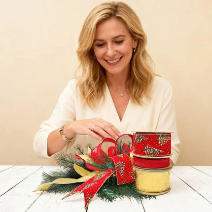 A Christmas decor, featuring ribbons: red with glitter pine patterns, red and metallic gold, all arranged on green pine.
