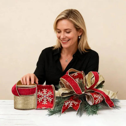 A woman presents a 3-roll Christmas ribbon set and a gorgeous ribbon bow, featuring red-gold snowflake, embossed, and metallic designs for stunning holiday projects.