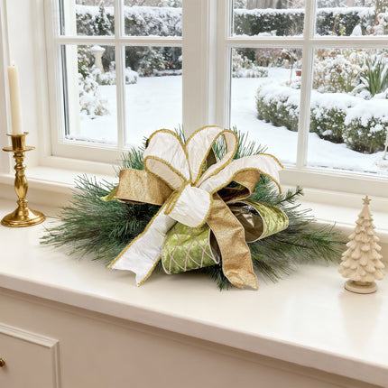 Christmas bow on windowsill with snowy garden view, featuring white, gold, green ribbons, adds festive luxury.