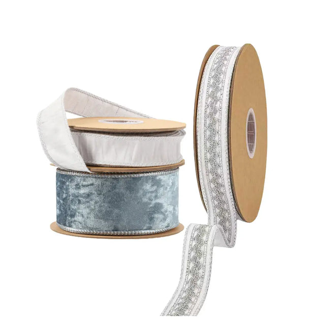 Assorted ribbon spools (blue velvet, white with silver embroidery, textured white) for holiday decorating, gift wrapping, crafts.