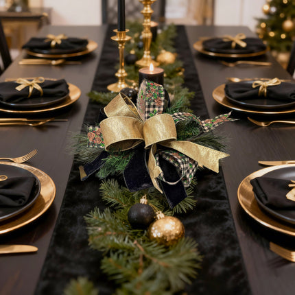 Elegant dining table decor: black/gold ribbon bows, pine sprigs & holiday accents.
