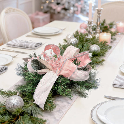 Dining table decor: pink ribbon bow + pine/candles – cozy holiday style.