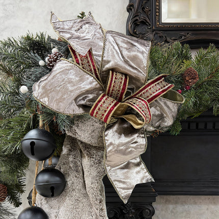 Silver shimmer bow with red-gold embroidered ribbon, evergreen foliage, luxurious detail.