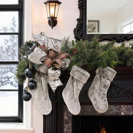 Mantel decor: silver shimmer bow (red-gold embroidered), plush gray stockings, evergreen.
