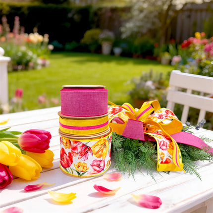 Vibrant tulip print, yellow-pink velvet stripe, and bright pink linen wired ribbon bundle arranged into a fresh spring bow on a garden table.
