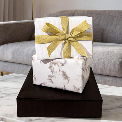 Textured white gift wrap with a gold glitter ribbon bow, for modern home gifting.