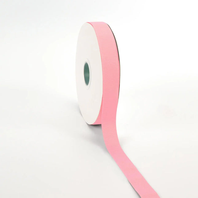 Spool of pink grosgrain ribbon, unrolled to display its textured weave.