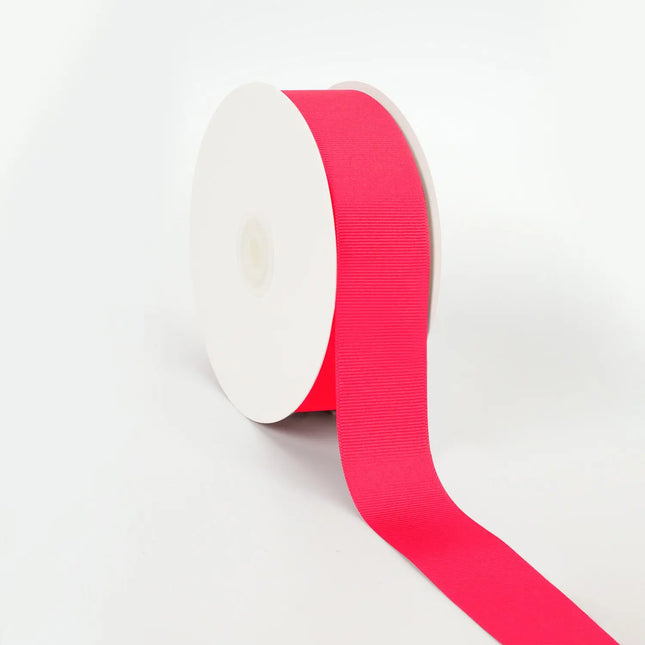 Spool of Shocking Pink grosgrain ribbon, unrolled to display its textured weave.