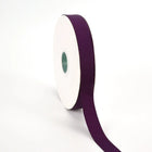 Spool of plum grosgrain ribbon, unrolled to display its textured weave.