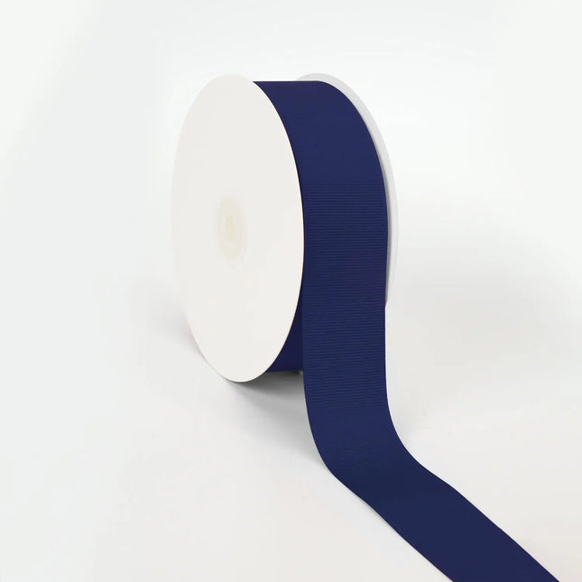 Spool of navy grosgrain ribbon, unrolled to display its textured weave.