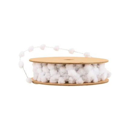 A spool of white pom-pom ribbon with fluffy, round pom-poms strung along a delicate thread.