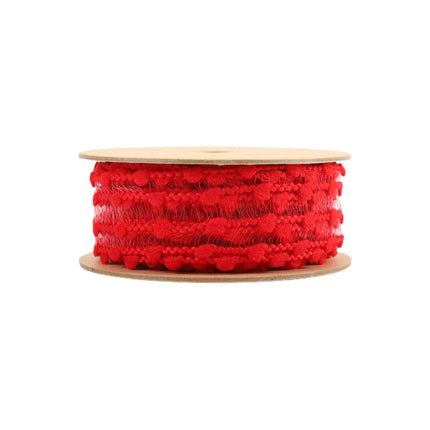 The roll of red ornamental ribbon, with a design of sheer material adorned with red, pom pom design with four rows.