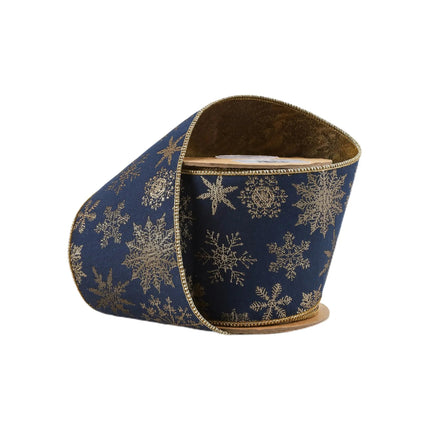 A roll of 4" wired jacquard ribbon, navy blue with intricate gold snowflake patterns, showcasing elegant craftsmanship.