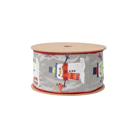 A roll of ribbon displays an embroidered pattern of snowmen on a gray surface with red edge stitching.