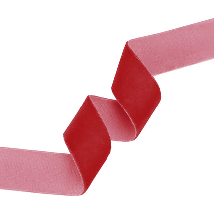 Curled scarlet velvet ribbon: plush red front, soft pink backing – elegant craft decor.