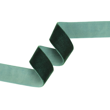 Dark green velvet ribbon on a brown spool, perfect for Christmas decor and creating upscale party favor ties with its rich, elegant finish.