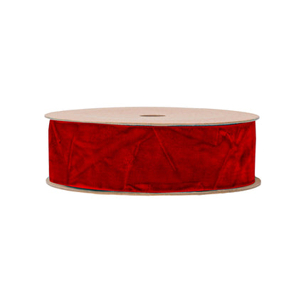 Red velvet ribbon on a spool, perfect for adding an opulent touch to holiday decorations and DIY crafts.