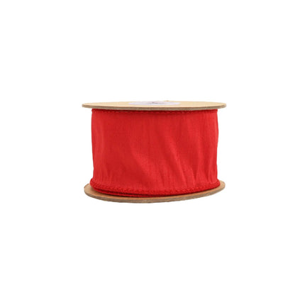 A spool of red ornamental ribbon, with a smooth, vibrant fabric, great for decorations or DIY projects.