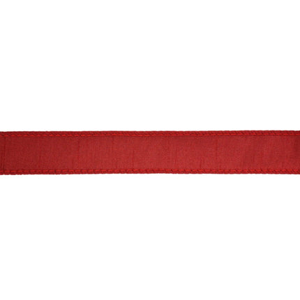 A piece of red decorative ribbon with a woven texture and stitched edges, suitable for Christmas decor.