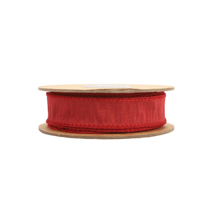 Red ribbon roll on wooden reel, detailed stitching, lush texture, ideal for holiday gifting.
