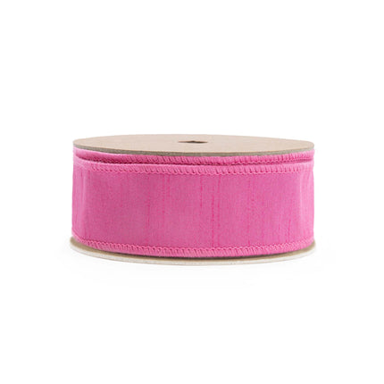 A spool holds a reversible pink textured ribbon with a red reverse, ideal for elevating decorations and crafting.