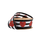 Roll of wired ribbon (black/white stripes + red glitter hearts) partially unspooled on cardboard spool.