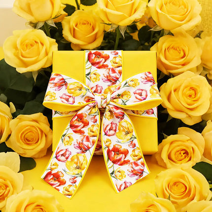 Yellow gift box wrapped with a vibrant tulip print wired ribbon bow, surrounded by bright yellow roses for cheerful spring gifting decor.