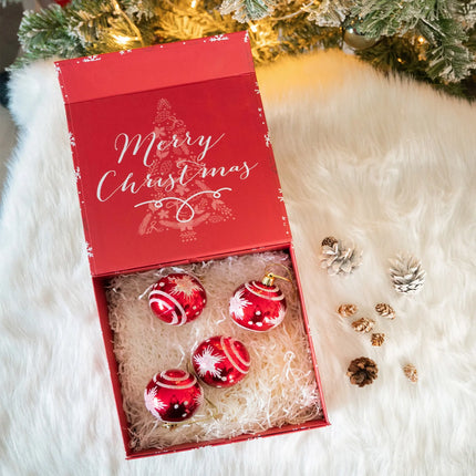 Open red snowflake gift box with "Merry Christmas" lid. Holds ornaments—cozy holiday decor.