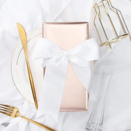 Rose gold matte-wrapped gift + large white bow; elegant gifting.