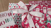 Gifts shine in holiday paper—reversible designs, Santa/red-green-white hues, premium durable, wraps smoothly, presents glow under the tree.